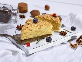 två bakad kakor napoleon med grädde på en vit trä- styrelse foto