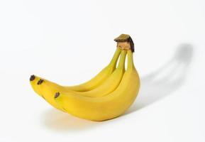 knippa av gul mogen bananer i skala på en vit bakgrund foto