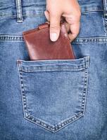 brun läder handväska lögner i de tillbaka ficka av blå jeans foto