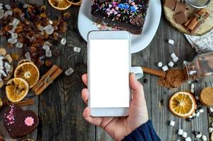 kvinna hand innehav en smart telefon på de tabell, vit tom skärm foto