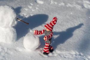 liten leksak dvärg bygger en snögubbe foto