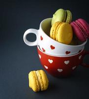 kakor av mandel mjöl macarons i en vit keramisk kopp foto