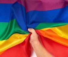 manlig hand innehar en regnbåge flagga en symbol av de HBTQ gemenskap foto