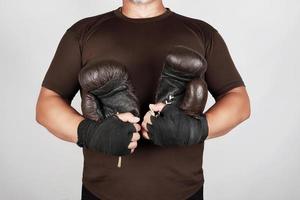 vuxen man i brun sport enhetlig innehar en par av brun årgång tillfällig boxning handskar foto