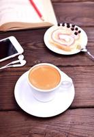 kopp av kaffe och en mobil telefon på en brun tabell foto