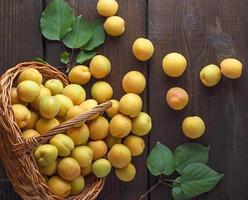 mogen gul aprikoser spridd från en korg- korg foto