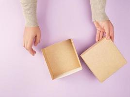 flicka öppnas en brun fyrkant låda på en lila bakgrund foto