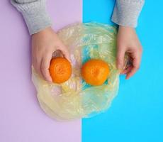 två mogen orange mandariner lögn i en transparent plast väska foto