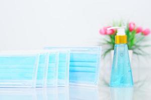 medicinska masker och alkohol gel flaska sanitizer hand agent vit bakgrund foto