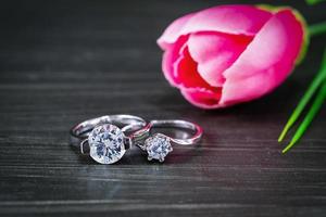 diamant bröllop ringar med tulpan blomma på svart bakgrund foto