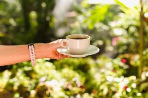 kvinna hand innehav en kopp av kaffe utomhus. foto