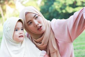 muslimska mor och dotter tar en glad selfie i parken