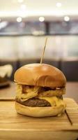 nötkött bringa burger som innehålla bearnaise sås, tomat, njuta av, lök ringar och mozzarella ost. foto