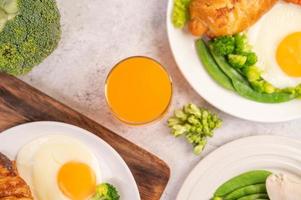 frukostspridning av kyckling, stekt ägg, broccoli, morötter, tomater och sallad foto