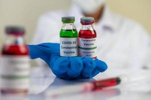 forskare som visar injektionsflaskor med vacciner för att skydda mot covid-19