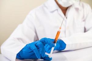 forskare som bär masker och handskar som håller en spruta med ett covid-19-vaccin