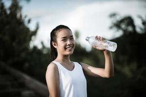 ung fitness tonåring håller vattenflaska efter att ha kört träning foto