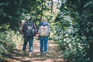 ungt par som går med ryggsäckar i skogen foto