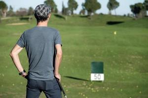 golfare på ryggen lutad på en golfklubb som tittar på horisonten foto