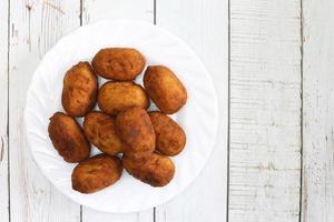 stekt kycklingkroketter på en vit maträtt på en träbakgrund. foto