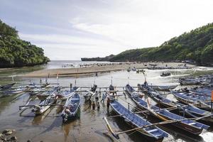 baron strand i gunung kidul, indonesien med besökare och traditionell båt. yogyakarta, indonesien - januari, 2023. foto