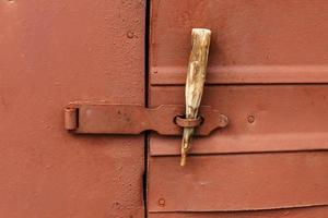 spärr på de järn dörr. en trä- pinne är infogad istället av en hänglås. foto