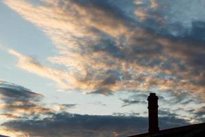 skorsten silhuett mot de solnedgång himmel. skorsten på de tak av de hus. foto