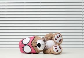 brun teddy Björn sitter med en bandage för sovande på en vit tabell foto
