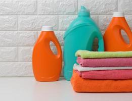 plast flaskor med flytande rengöringsmedel och vikta handdukar på en vit hylla. bad interiör foto