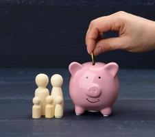 trä- familj figurer och rosa keramisk nasse Bank på blå bakgrund foto