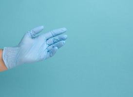 läkares hand i en blå medicinsk handske innehar ett objekt på en blå bakgrund foto