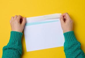 kvinna hand innehar vit papper kuvert på ett orange bakgrund, topp se. sändning och tar emot korrespondens foto