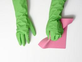 hand i en grön sudd handske innehar en mjuk svamp för rengöring ytor på en vit bakgrund foto
