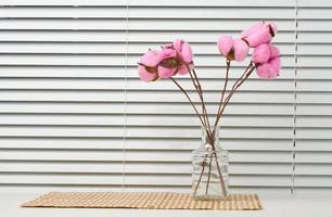 glas transparent vas med en bukett av rosa bomull blommor på en vit tabell foto
