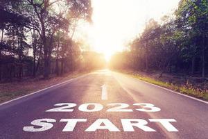 tömma asfalt väg och ny år 2023 begrepp. körning på ett tömma väg till Start 2023 med solnedgång. foto