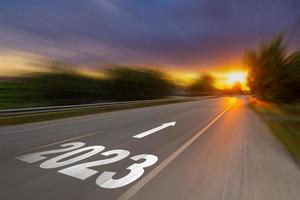 rörelse fläck tömma asfalt väg och ny år 2023 begrepp. körning på ett tömma väg till mål 2023 med solnedgång. foto