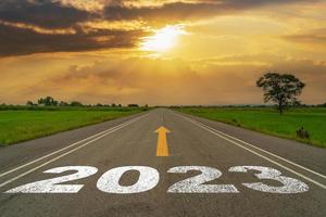 tömma asfalt väg och ny år 2023 begrepp. körning på ett tömma väg till mål 2023 med solnedgång. foto