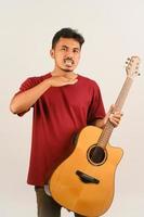porträtt av ung asiatisk man i röd t-shirt med ett akustisk gitarr isolerat på vit bakgrund foto