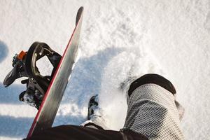 okänd snowboardåkare promenad på pulver dag på färsk snö med snowboard till snålskjuts kulle foto