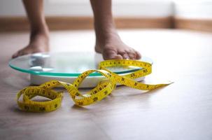 en kvinna på en skala de gul tejp är i fokus. vikt förlust diet begrepp. foto