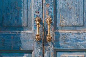 arkitektonisk detalj av en årgång mässing dörr hantera ,årgång antik dörr hantera på de gammal blå trä- dörr foto