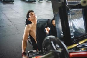 asiatisk män idrottare håller på med ben Tryck övningar med maskiner till stärka muskler för hälsa vård på de Gym stadion foto