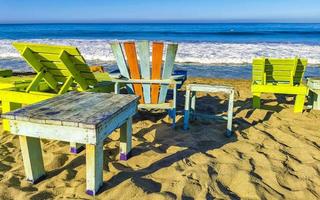 palmer parasoller Sol solstolar strand vågor puerto escondido Mexiko. foto