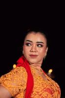 javanese kvinna i en traditionell orange klänning medan bär smink och en röd scarf på en dansa festival foto