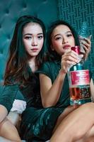 asiatisk kvinnor innehav ett alkohol flaska i deras hand i de sovrum foto