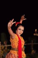 ett asiatisk traditionell dansare i ett orange klänning med en röd scarf och smink utför på de dansa festival foto