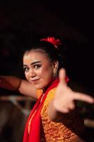 skön ansikte av ett indonesiska kvinna i smink medan dans en traditionell dansa i ett orange kostym under de festival foto