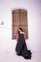 elegans kvinna i en svart klänning stående i främre av de rustik trä- fönster foto