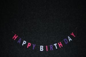 flerfärgad krans av brev Lycklig födelsedag på en mörk bakgrund. foto