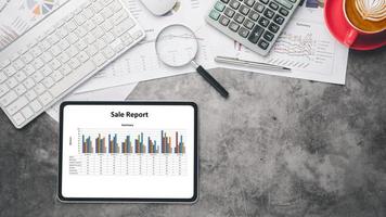 läsplatta med diagram och rapporter på kontor skrivbord arbetsplats. topp se platt lägga foto